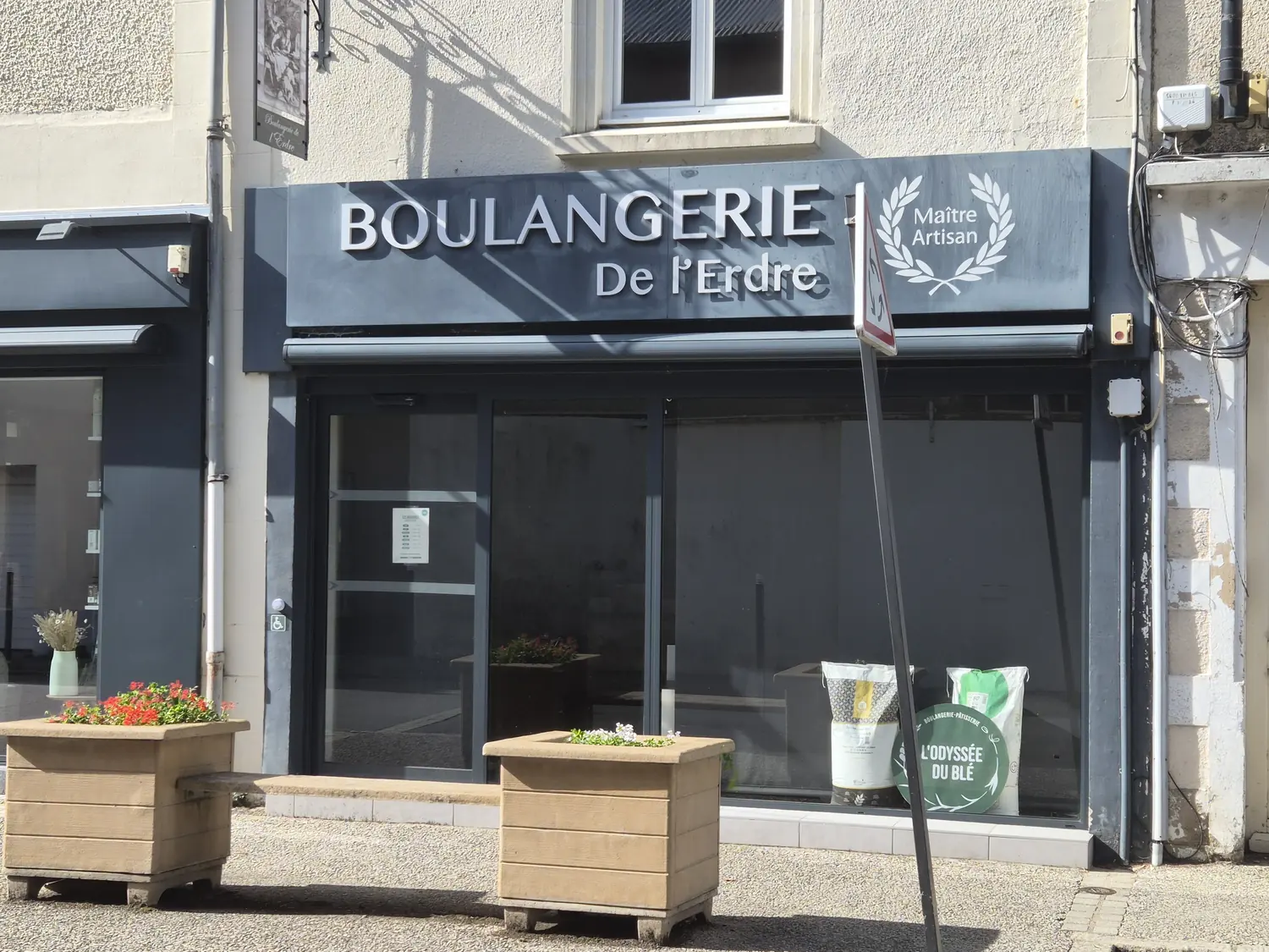 La boulangerie, 5 rue d'Anjou, pendant son changement d'enseigne en 2026 : le disque de « L'Odyssée du Blé » en vitrine, l'ancien nom encore au-dessus de la devanture.