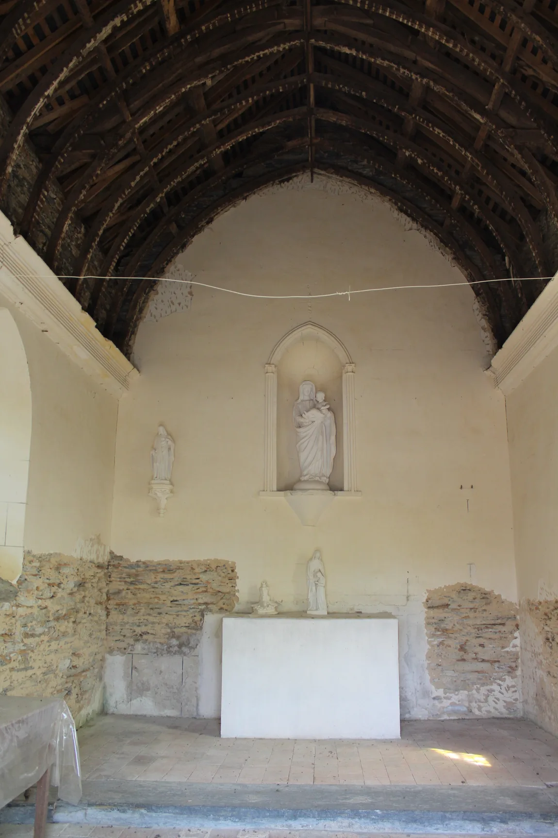 L'intérieur de la chapelle du Rosaire de Freigné : la charpente de bois apparente et la niche de Notre-Dame du Rosaire.