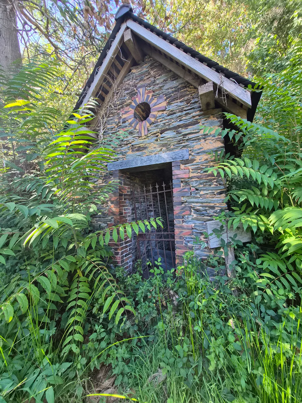 L'édicule de la fontaine Saint-Germain, sous les fougères, en contrebas de la chapelle (septembre 2026).