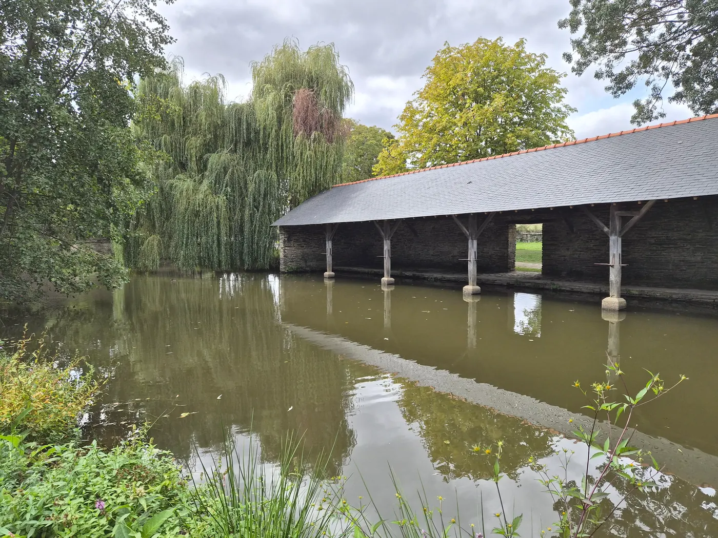 Le lavoir couvert, sur la rive du plan d'eau, en septembre 2026.