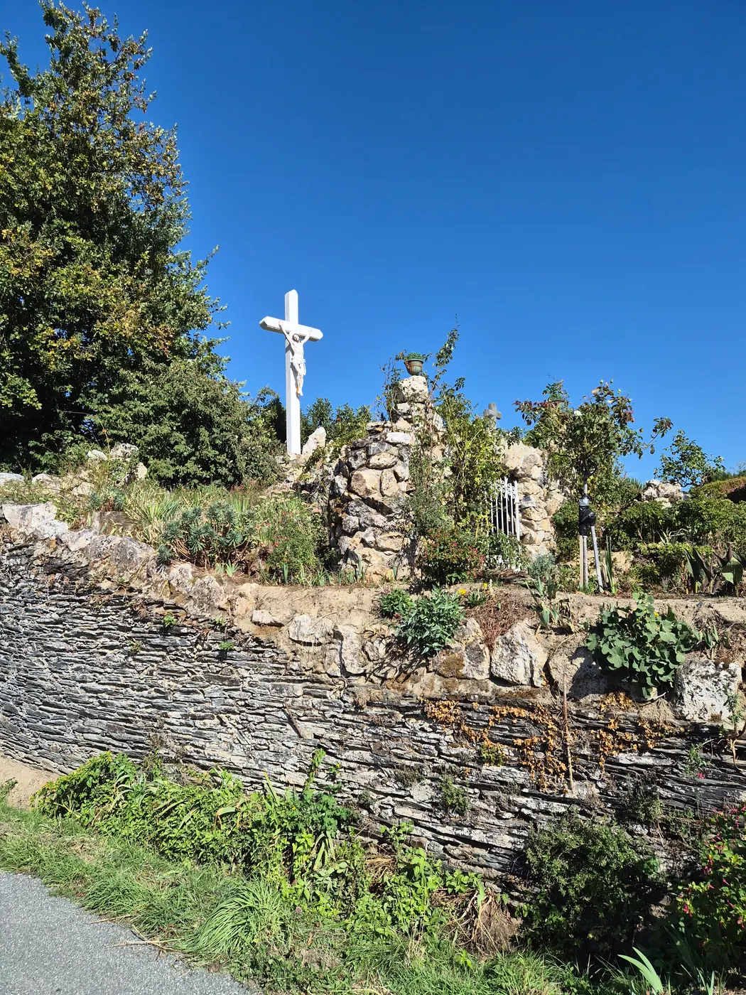 Le calvaire dressé au sommet de la grotte, au-dessus de la rue (septembre 2026).